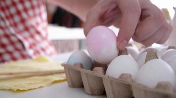 Young man coloring eggs sitting at the kitchen at home video