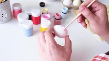 Young man coloring eggs sitting at the kitchen at home video