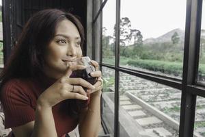 Portrait of joyful young woman enjoying a cup of tea at home. Smiling pretty girl drinking telang tea in rainy season. photo