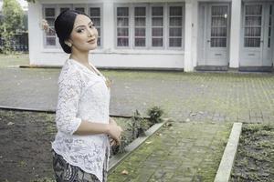 un joven indonesio mujer con un contento exitoso expresión vistiendo un blanco kebaya. de kartini día concepto. foto