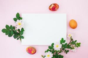 Colored eggs of branches with cherry or apricot branch with white paper for text. Easter.  Copy space photo