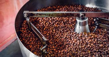 granos de café aromáticos recién tostados sobre una moderna máquina tostadora de café. foto