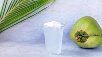 Ice coconut water drink in a plastic glass and coconut on white background photo