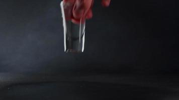 une caucasien homme main prend une verre de l'eau contre une noir Contexte. proche en haut video