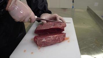 Carnicero cortes Fresco carne de vaca carne con agudo filete cuchillo en carnicería tienda. cerca arriba video