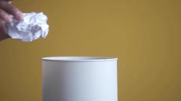 Throwing crumpled paper ball in a bin close up video