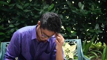 Young man suffering headache, sitting on a park bench video