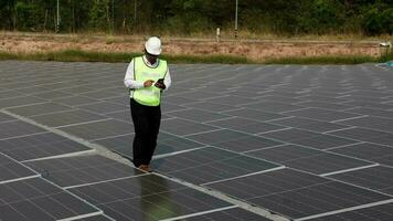 sustentável verde energia instalação. técnicos dentro laranja uniforme e capacetes trabalhando com solar painéis em a energia Fazenda. video