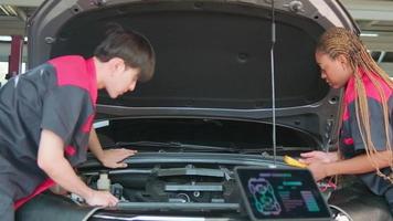 Two professional automotive mechanical partners check and repair an EV car battery and hybrid engine at a maintenance garage, expert electric vehicle service, and fixing occupations auto industry.