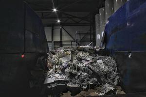 Shredding waste paper conveyor belt for recycling wrap, garbage and cardboard against bales of used carton boxes collected for reuse at industrial plant factory. Zero waste, eco-friendly concept photo