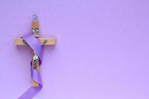 cristiano religioso de madera cruzar crucifijo con Violeta cinta en púrpura antecedentes. católico religión símbolo. bueno viernes, prestado estación, palma domingo, ceniza miércoles y santo semana concepto foto