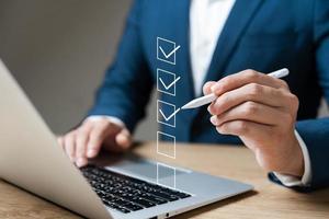 Business performance checklist concept, businessman using laptop doing online checklist survey, filling out digital form checklist. photo