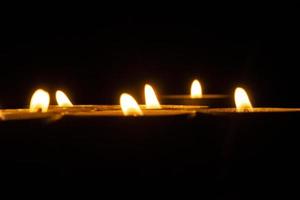 Candles burn in dark. Candle flames. Lights on black background. photo