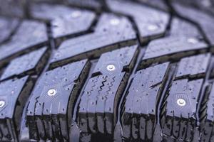 Winter tires with spikes on a black background close-up, safety during winter driving, winter studded rubbe photo