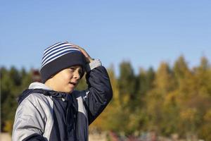 Portrait of a cute Caucasian boy 5 years old in a knitted striped hat on a walk on an autumn sunny day photo