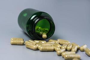 Capsules with vitamins and minerals are poured out of the jar on a gray background. Close-up photo