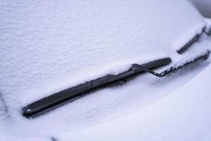 Snow-covered car windshield, wiper blade in fluffy First snow photo