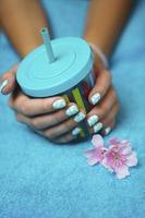 Vertical photo of beautiful women's hands with colored manicure and a multicolored cup with a drinking tube