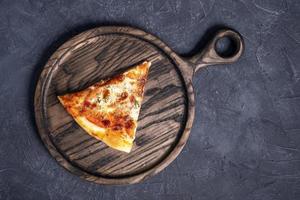 A piece of delicious hot pizza on a wooden oak board. Top view of a delicious freshly baked hot pizza photo