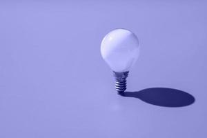 White minion light bulb on violet background, demonstration of the trending color of the year 2022 photo