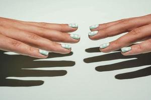 Two beautiful female hands with colored manicure in turquoise tones are reaching out to each other photo