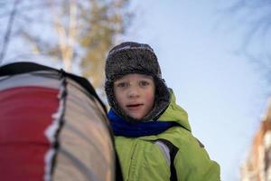 Funny Caucasian boy 5 years old rides in winter on a big inflatable cheesecake photo