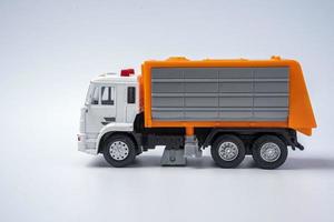 A toy garbage truck with an orange body on a white background. photo