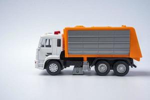 A toy garbage truck with an orange body on a white background. photo