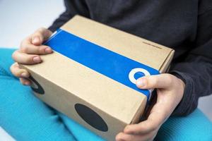 The child holds a cardboard box with a gift sent by the delivery service. photo
