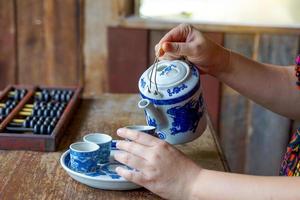 un foto esquina ese simula el té cultura de el chino gente. con asiático mujer jugando chino roles utilizar tu mano a verter té dentro un taza para té con un continuar patrón, cuales es un popular modelo.