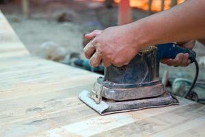 Carpenters use a sander to sand the surface of the wood to smooth the woodwork before painting. Soft and selective focus. photo