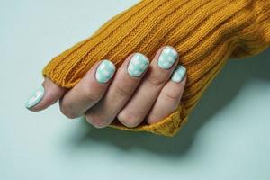 Beautiful female fingers with colored manicure with clouds, the sleeve of a warm wool sweater mustard color photo