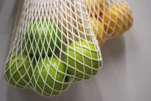 string bags with oranges and green apples, the concept of waste-free production photo