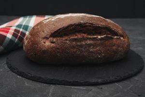 Freshly baked warm delicious rye round bread close-up and a kitchen checkered towel. The concept of healthy eating photo