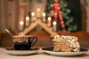 A piece of delicious beautiful cake decorated with cream and banana slices and a cup of tea photo