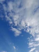 White clouds in the blue sky. Beautiful bright blue background. Light cloudy, good weather. Curly clouds on a sunny day. photo