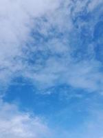 White clouds in the blue sky. Beautiful bright blue background. Light cloudy, good weather. Curly clouds on a sunny day. photo