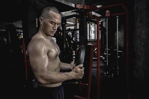 retrato de asiático hombre grande músculo a el gimnasio,tailandia gente,entrenamiento para bueno cuerpo saludable peso entrenamiento, fitness a el gimnasio concepto, broma a abdominal músculos foto
