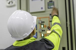 Electrical engineer man checking voltage at the Power Distribution Cabinet in the control room,preventive maintenance Yearly,Thailand Electrician working at company photo