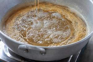 Making Thai dessert Golden Egg yolk threads or Foi Thong in a pot with boiling syrup. photo