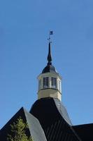 weather vane rooster on the spire of an old house, high in the blue sky photo