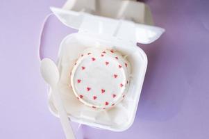 A small bento cake in eco packaging with a wooden spoon on a purple background photo