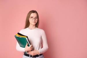 linda estudiante niña con lentes sostiene carpetas en rosado antecedentes foto