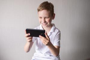 The boy is sitting on a chair and playing a video game console photo