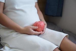 Young Asian Pregnant Woman using rattle toy to play with her unborn baby photo