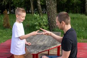 A cute boy is playing a game with his dad. shows signs with his hands photo