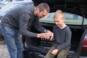 Dad teaches his cute son to use a car repair tool photo