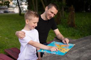 Cute boy in a white T-shirt shows a map of the world to Dad photo