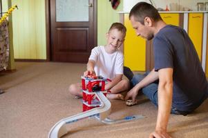 Cheerful dad plays with a cute boy at home in cars photo