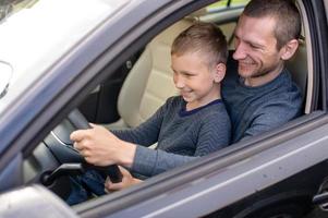 Dad shows his little son how to drive a car photo